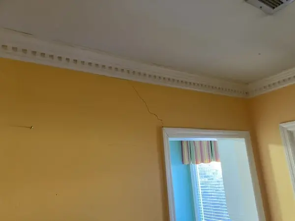 A diagonal crack in an interior wall near the ceiling.