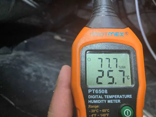 Checking crawl space air quality and humidity with a digital meter.
