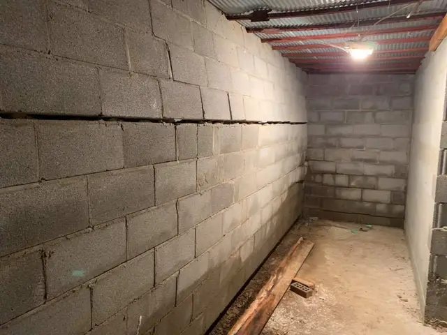 Ground Up Foundation Repair, Waterproofing and Concrete Leveling inspecting a bowing basement wall with a large horizontal