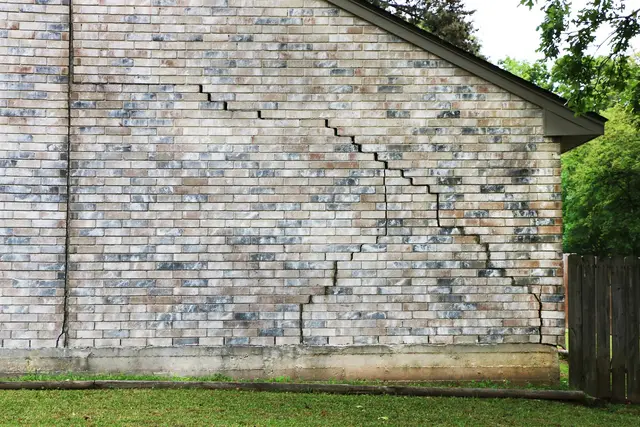 Ground Up Foundation Repair, Waterproofing and Concrete Leveling inspecting severe stair-step cracks in an exterior brick