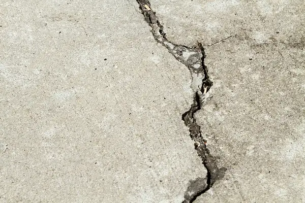 A jagged crack running across an exterior concrete slab.