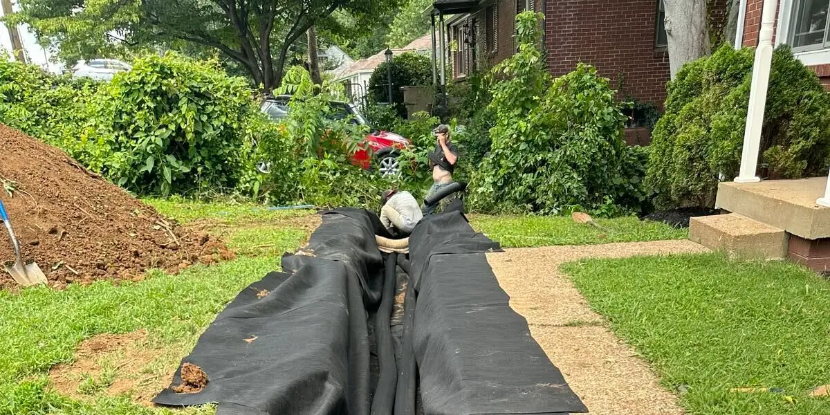 Ground Up Foundation Repair, Waterproofing and Concrete Leveling installing a french drain in a residential yard.