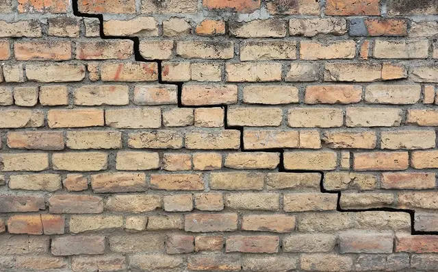 Ground Up Foundation Repair, Waterproofing and Concrete Leveling inspecting a stair-step crack in a brick foundation.