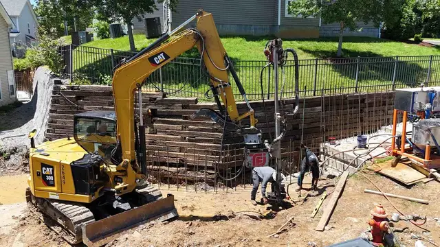 Ground Up Foundation Repair, Waterproofing and Concrete Leveling crew performing commercial foundation repair with an excavat