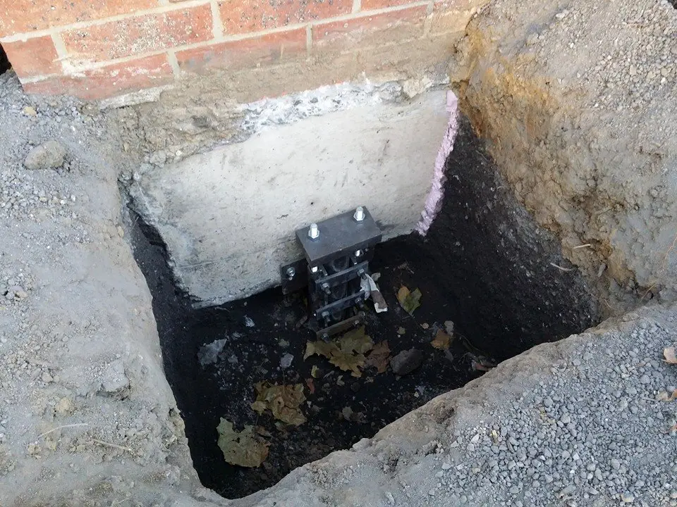 Ground Up Foundation Repair, Waterproofing and Concrete Leveling installing a steel pier foundation bracket.