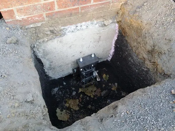 Ground Up Foundation Repair, Waterproofing and Concrete Leveling installing a steel pier foundation bracket.