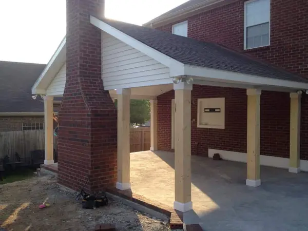 A finished concrete patio under a new patio cover at a brick home.