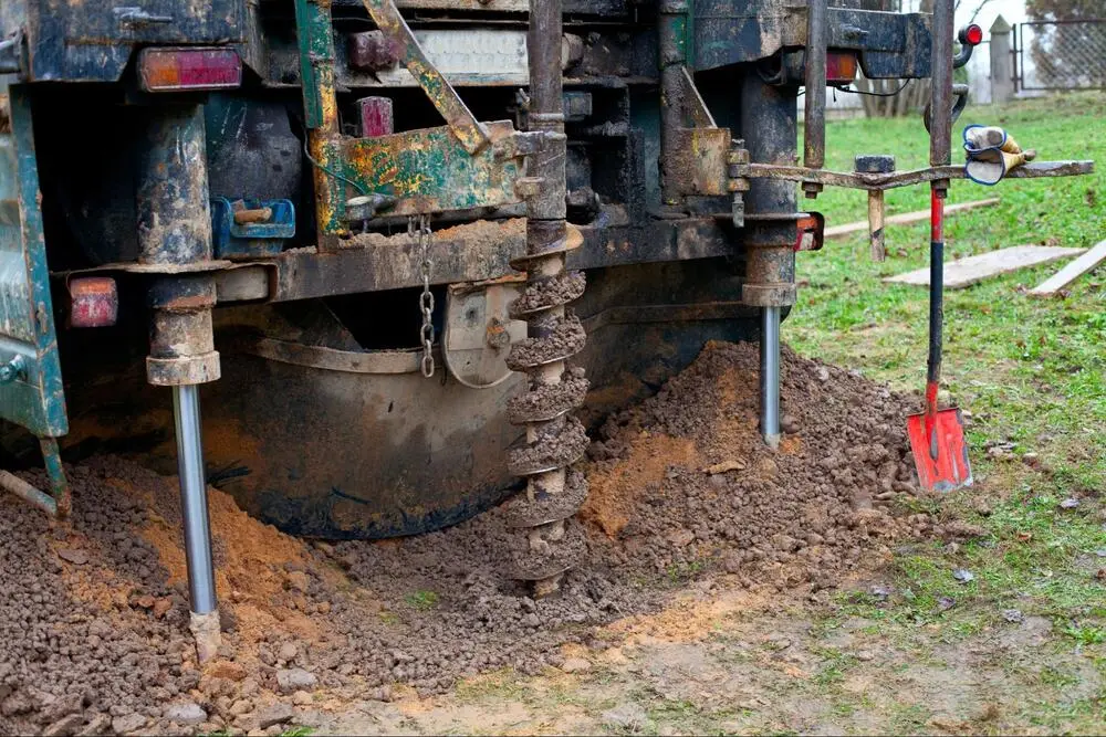 Ground Up Foundation Repair, Waterproofing and Concrete Leveling installing helical piers with a rotary drive head for deep