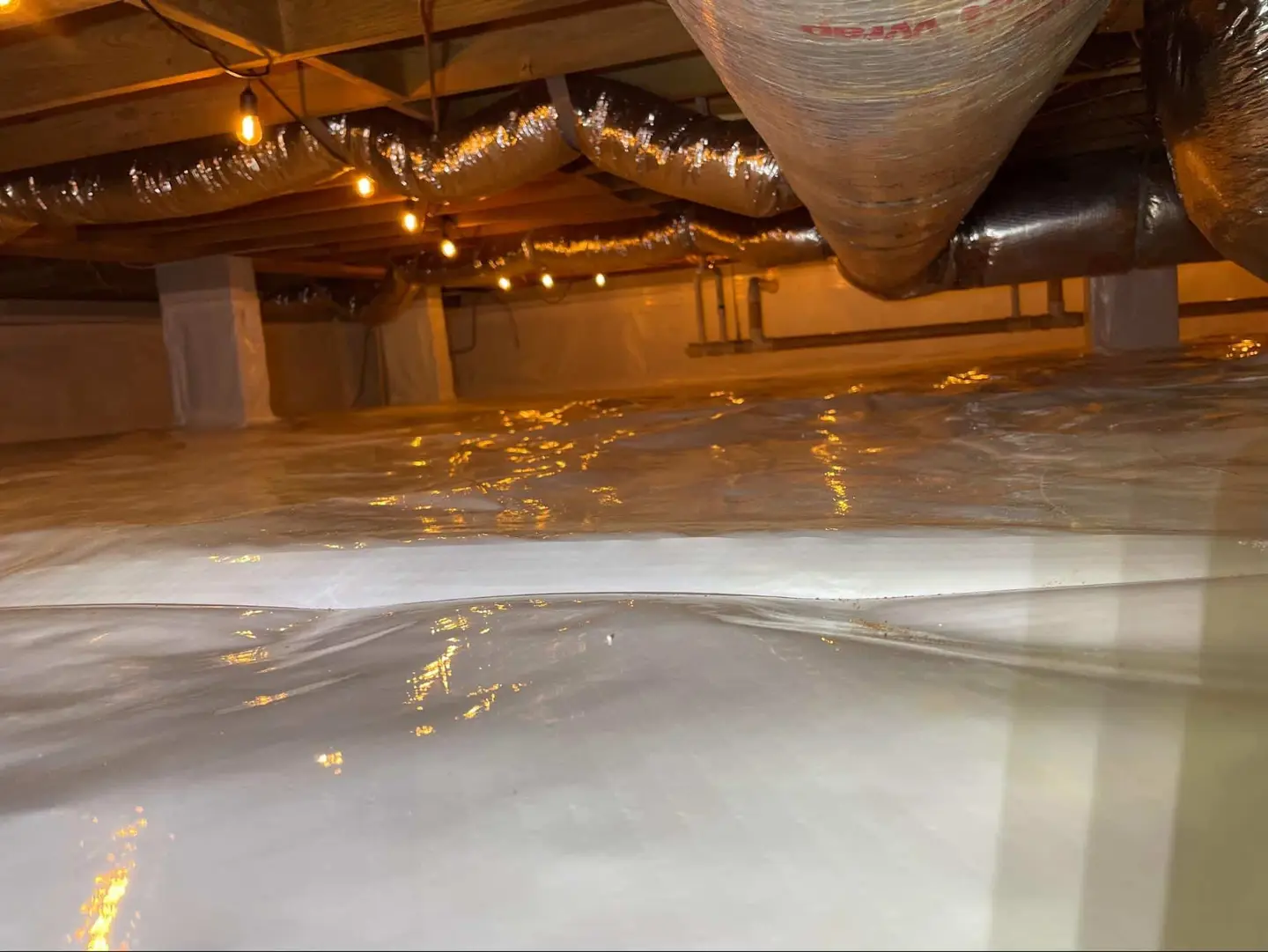 Ground Up Foundation Repair, Waterproofing and Concrete Leveling inspecting pooled water on a crawl space vapor barrier.