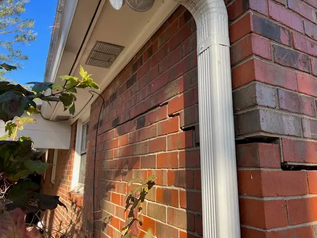 Ground Up Foundation Repair, Waterproofing and Concrete Leveling inspecting cracked bricks and shifting foundation due