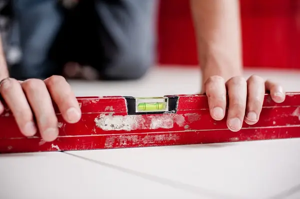 Ground Up Foundation Repair, Waterproofing and Concrete Leveling inspecting uneven concrete slabs with a spirit level.