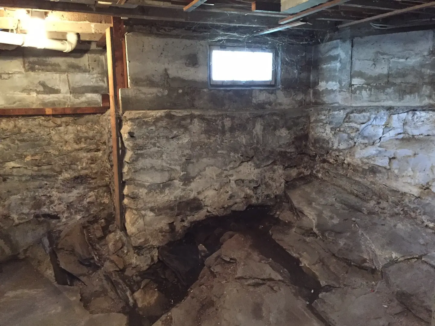 Ground Up Foundation Repair, Waterproofing and Concrete Leveling inspecting significant pooled water in an unfinished stone