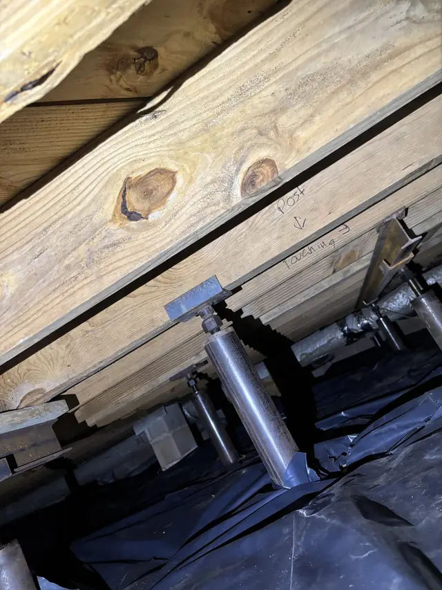 Ground Up Foundation Repair, Waterproofing and Concrete Leveling installing adjustable steel jacks to support sagging floor