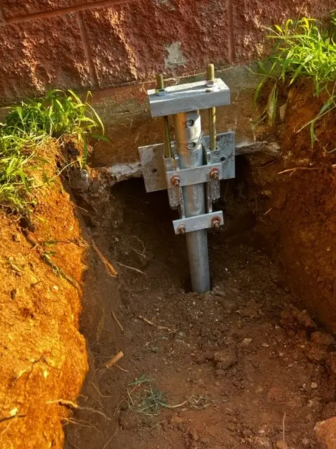 Ground Up Foundation Repair, Waterproofing and Concrete Leveling installing steel piers with a hydraulic ram to stabilize