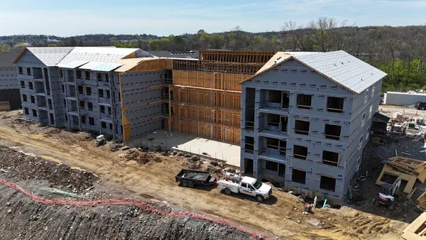 Aerial view of a multi-family apartment building under construction with a Ground Up Foundation Repair truck on site.