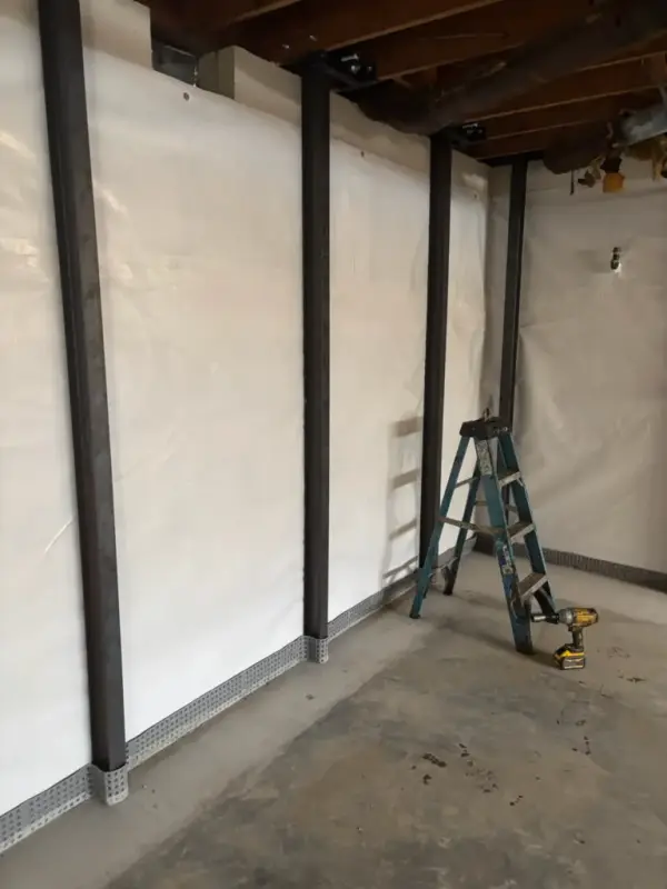 Ground Up Foundation Repair, Waterproofing and Concrete Leveling installing I-beam wall bracing and a vapor barrier