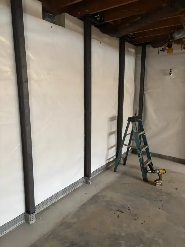 Ground Up Foundation Repair, Waterproofing and Concrete Leveling installing I-beam wall bracing and a vapor barrier