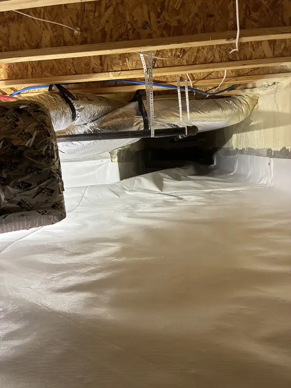 A sealed crawl space with the liner lapped up the foundation wall and around a duct penetration.